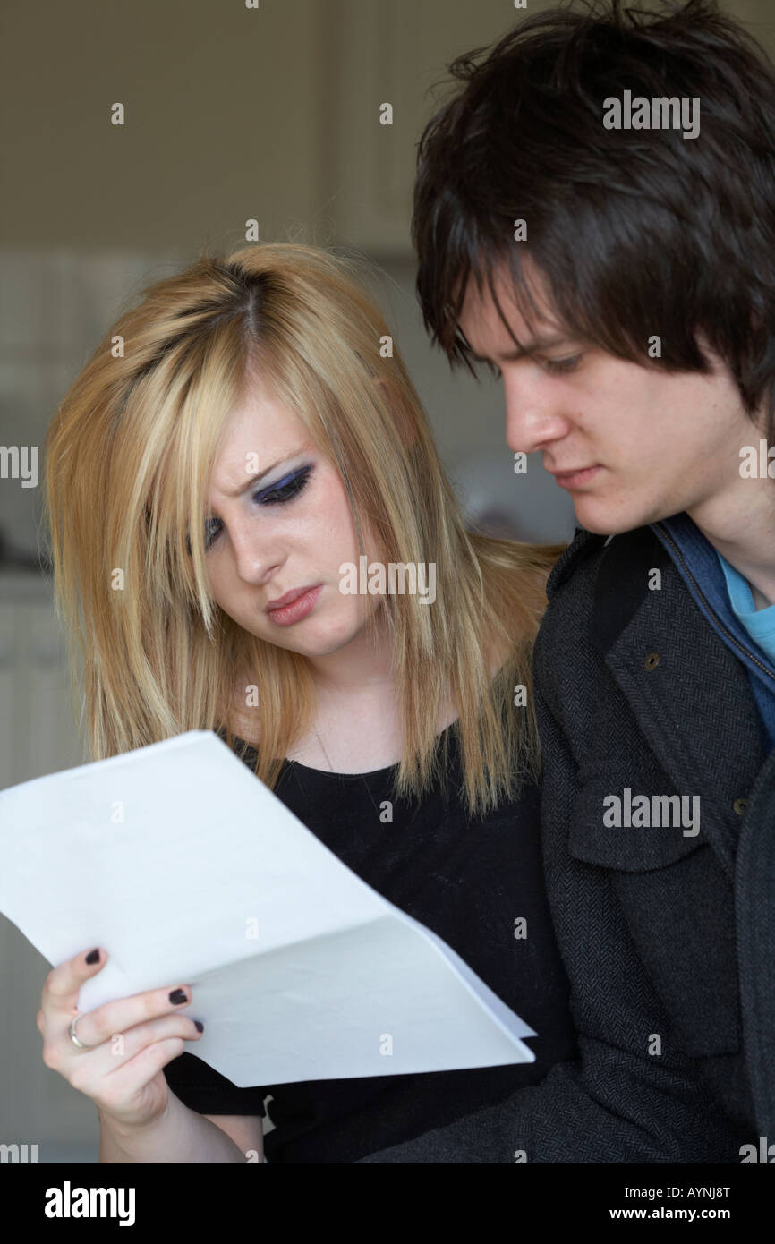 young teenage couple intently reading a document together in the kitchen of their bedsit Stock Photo