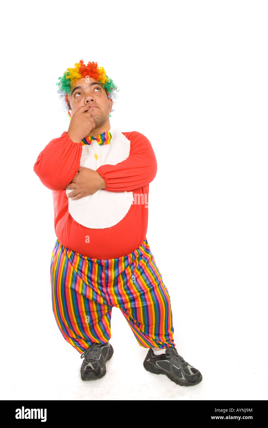 Full length portrait of an adult midget clown looking up finger in mouth against a white background Stock Photo