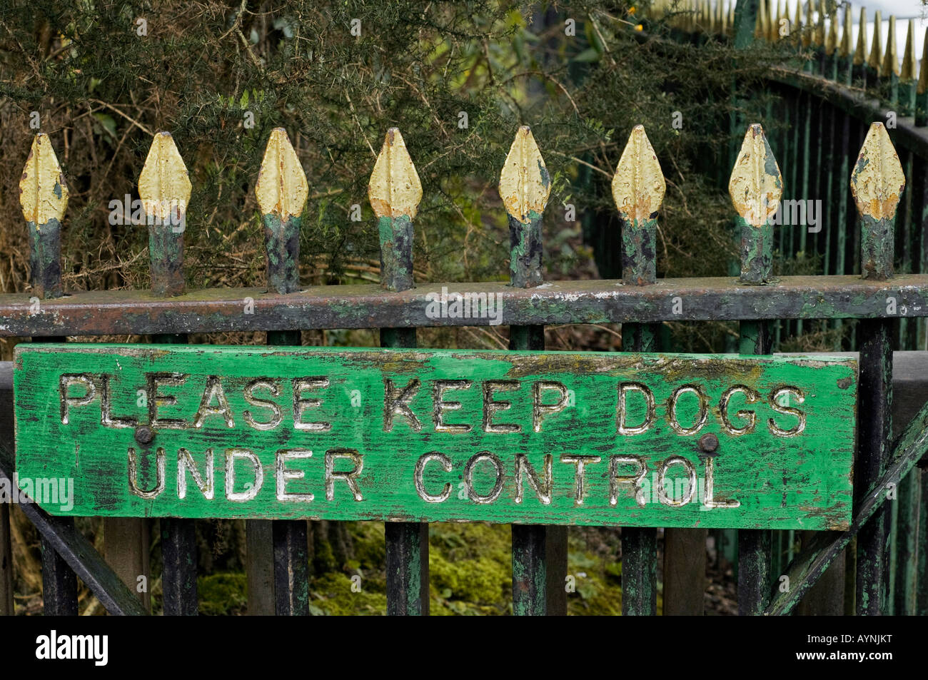 Weathered sign on fence Please Keep Dogs Under Control Stock Photo