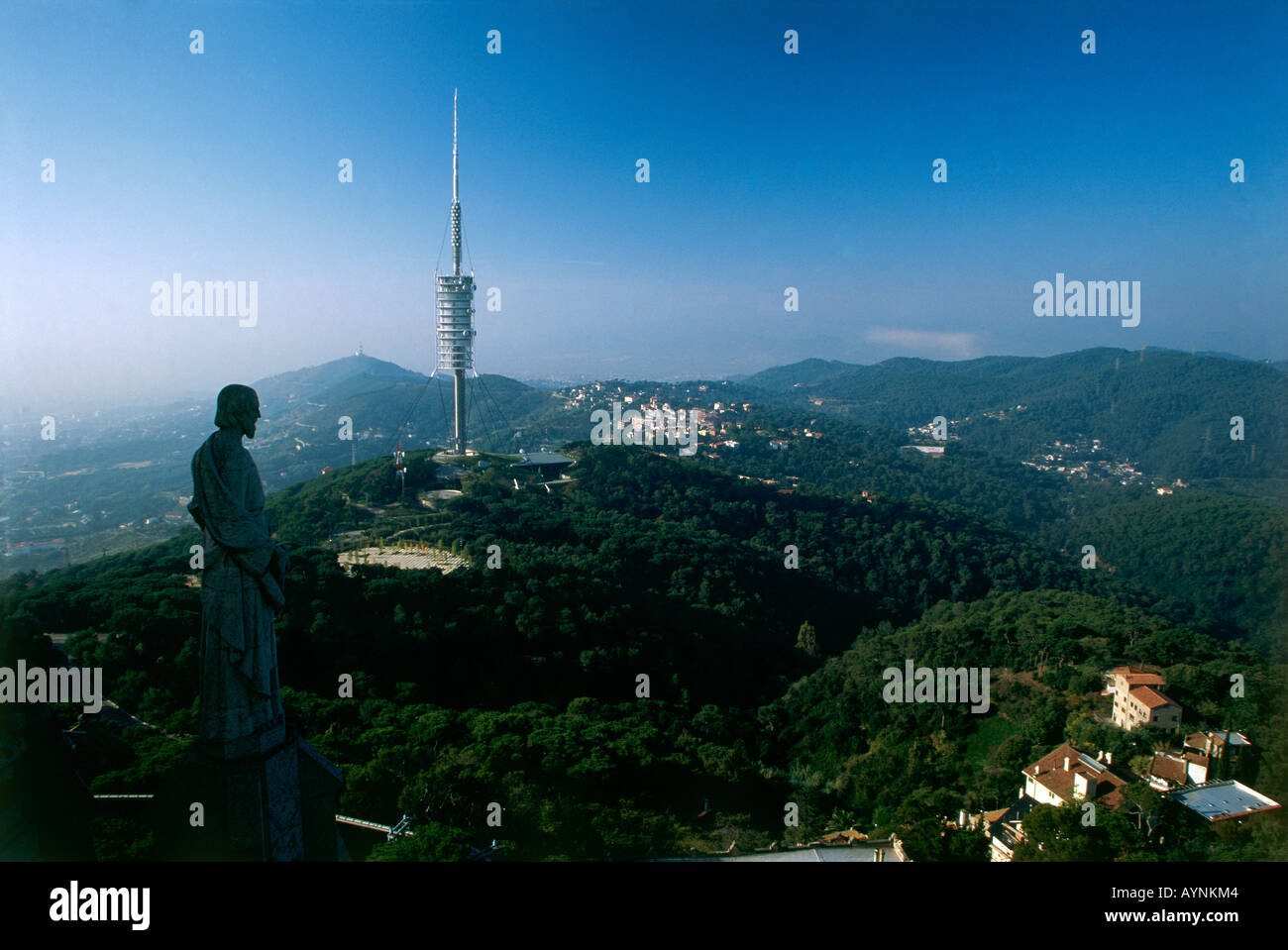 A statue poised on a rooftop gazes across at the Torre Collserola Sir Norman Foster s slender and dynamic eight hundred foot high tech telecommunications tower which was built for the Olympics and which looks down on Tibidabo Stock Photo