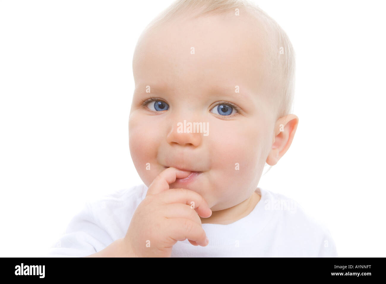 Cute baby looking into camera with a finger in his mouth contemplating his next mischief Stock Photo