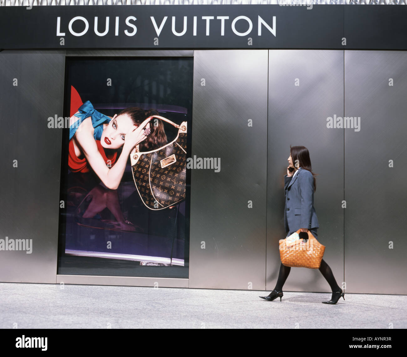 A woman walks pass a Louis Vuitton advertisement in a shopping