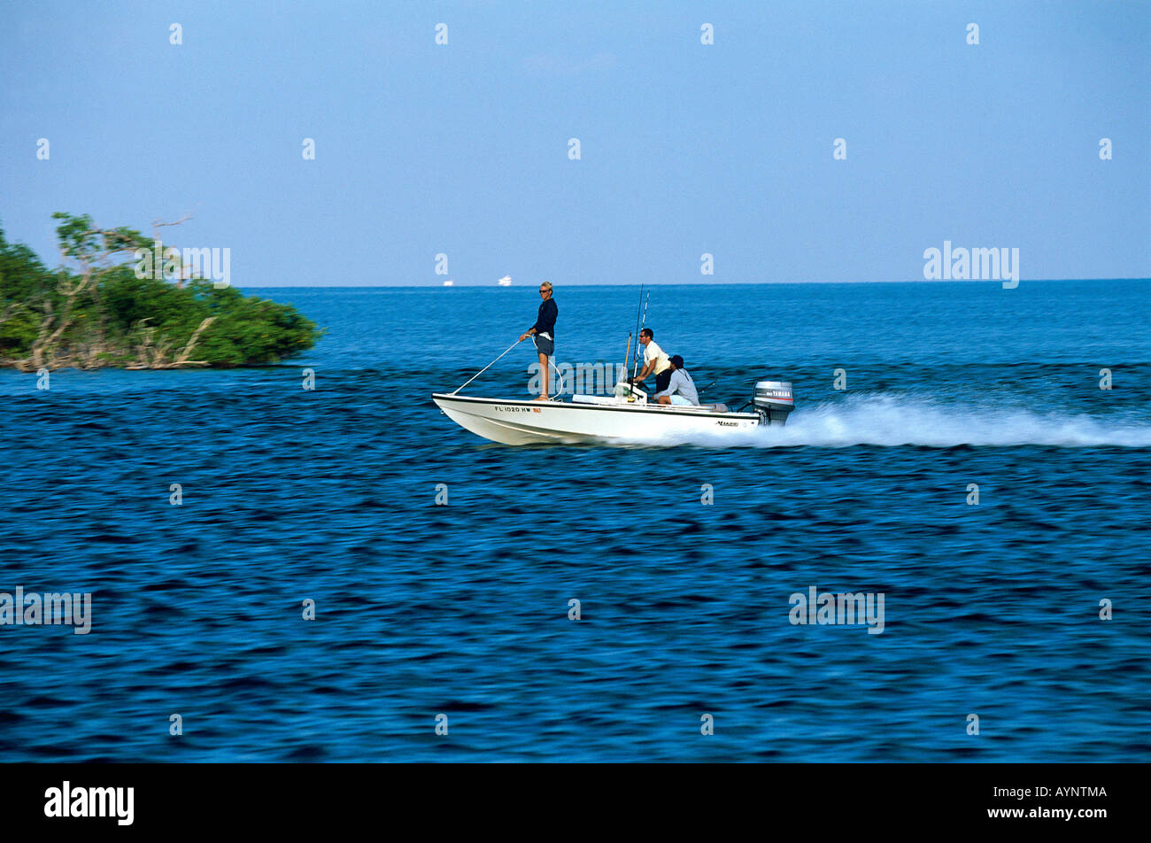 Causing quite a wake from their small launch a group of fishermen look for good casting sites in Biscayne National Underwater Park Stock Photo