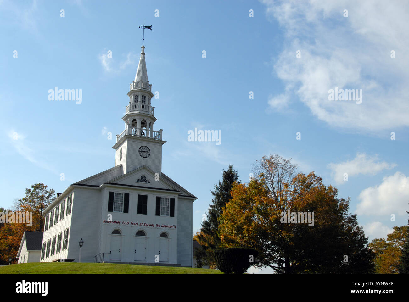 New England white clapboard hilltop church surrounded by autumn fall colored trees Stock Photo