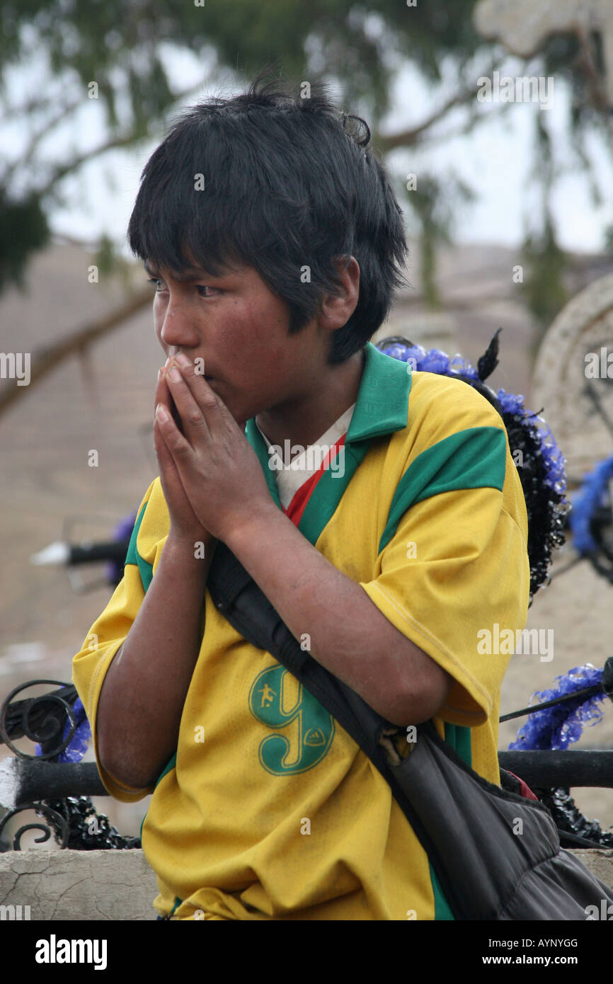 AChild praying in front of a grave specially decorated for the celebration of All Saints at the cemetery in Llallagua, Bolivia Stock Photo