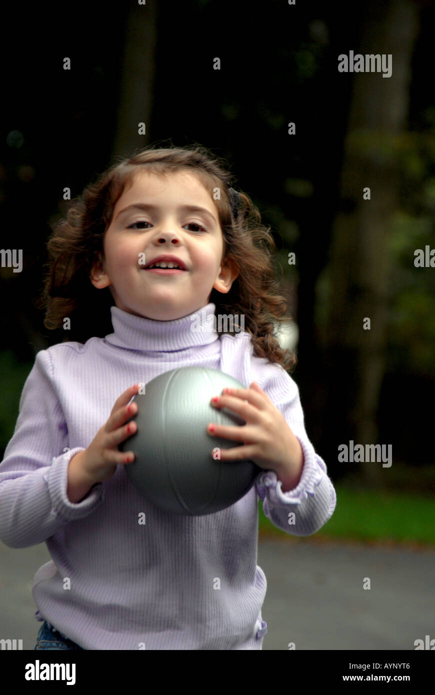 Smiling three year old girl poised to throw a basketball Stock Photo