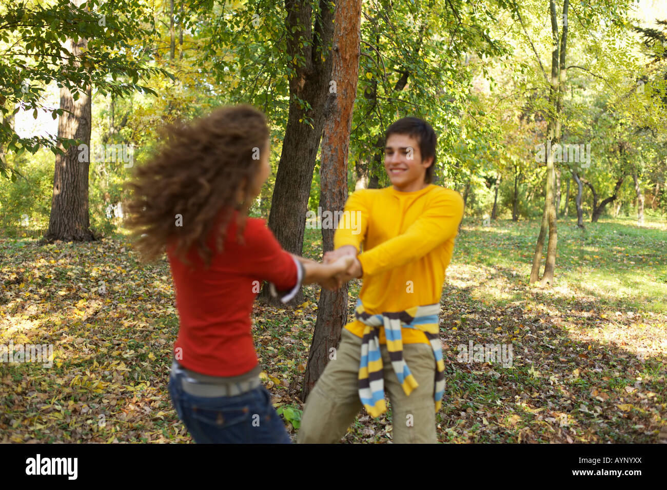 Teenage girl and teenage boy holding hands while dancing in the forest ...