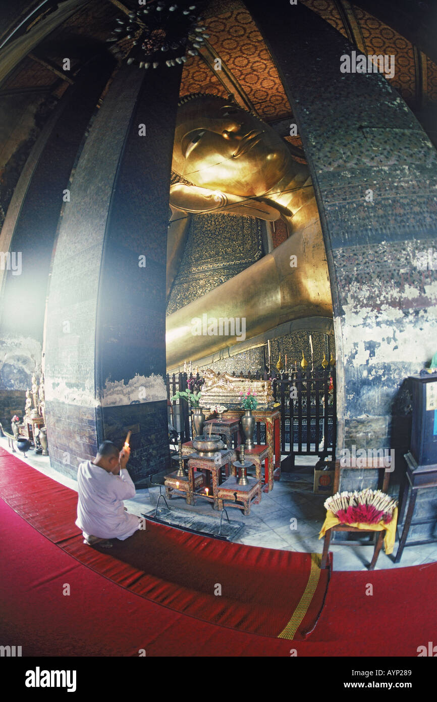 Buddhist monk burning prayer incense under Reclining Buddha at Wat Po in Bangkok Stock Photo Alamy