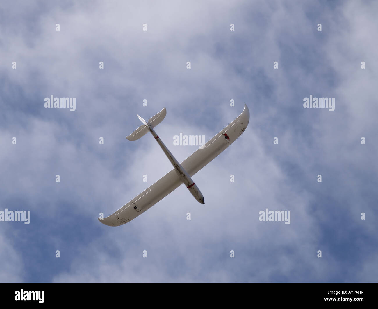 Remote controlled aeroplane flying in a blue sky with white fluffy clouds. Stock Photo