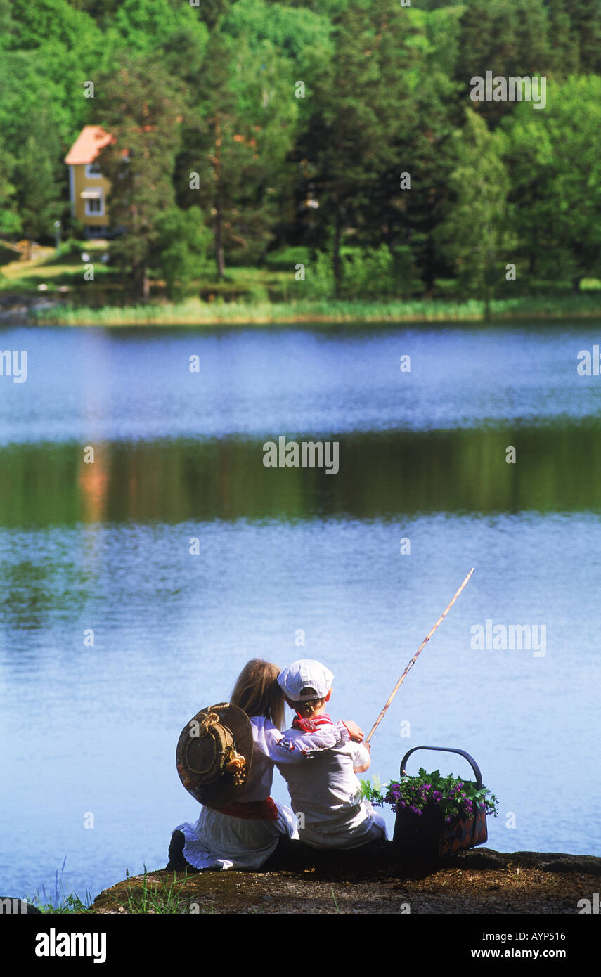 Boy and girl cuddling on lakeside fishing picnic in Sweden Stock Photo