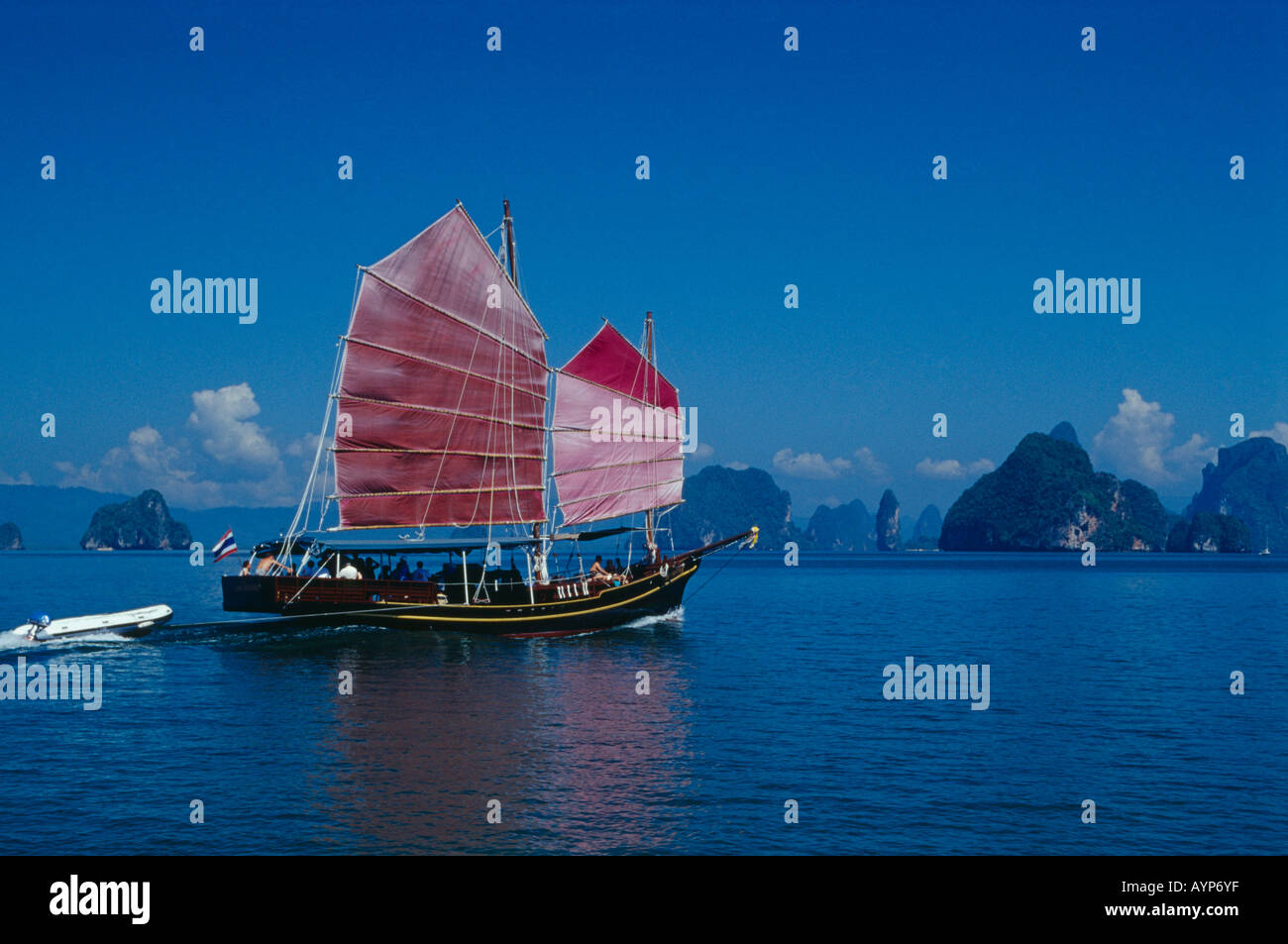 THAILAND Southeast Asia Phuket Tourist excursion Chinese Junk with pink sails reflected in deep blue water with karst islands Stock Photo