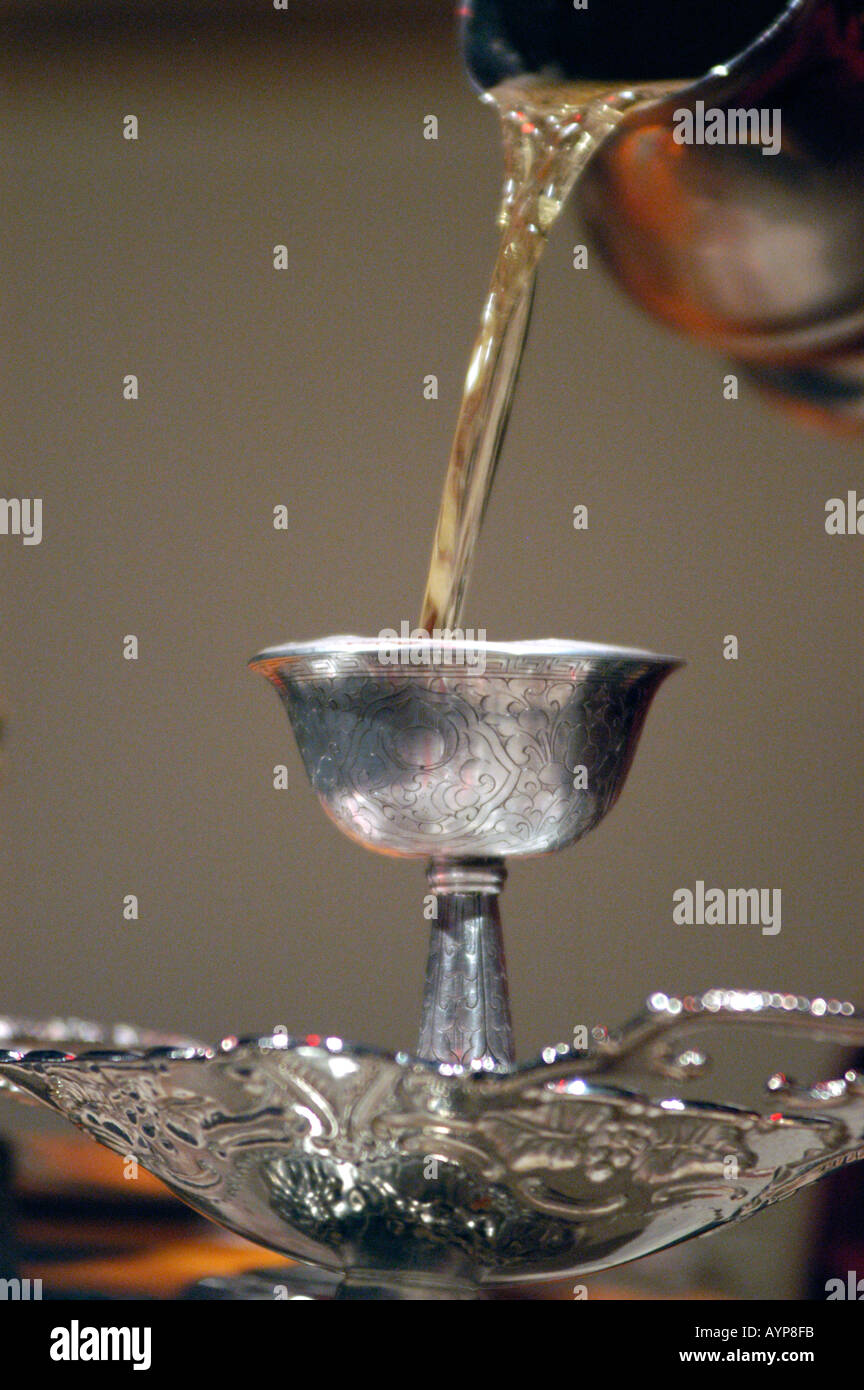 Pouring water into silver chalice during Tibetan Buddhist religious ceremony Stock Photo