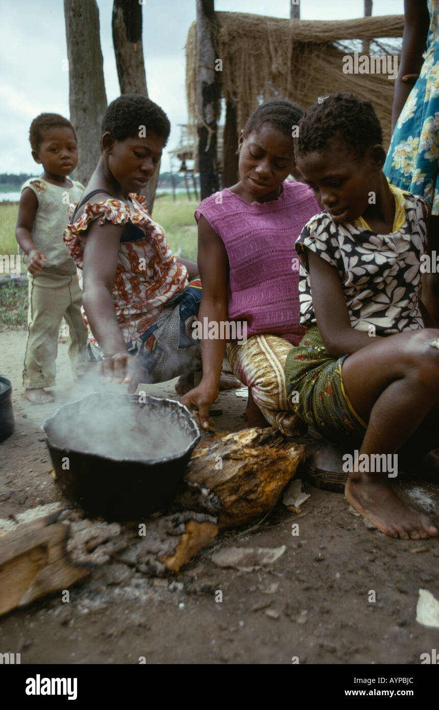 CONGO Central Africa Food Women with children cooking cassava in a pot over wood burning fire Stock Photo