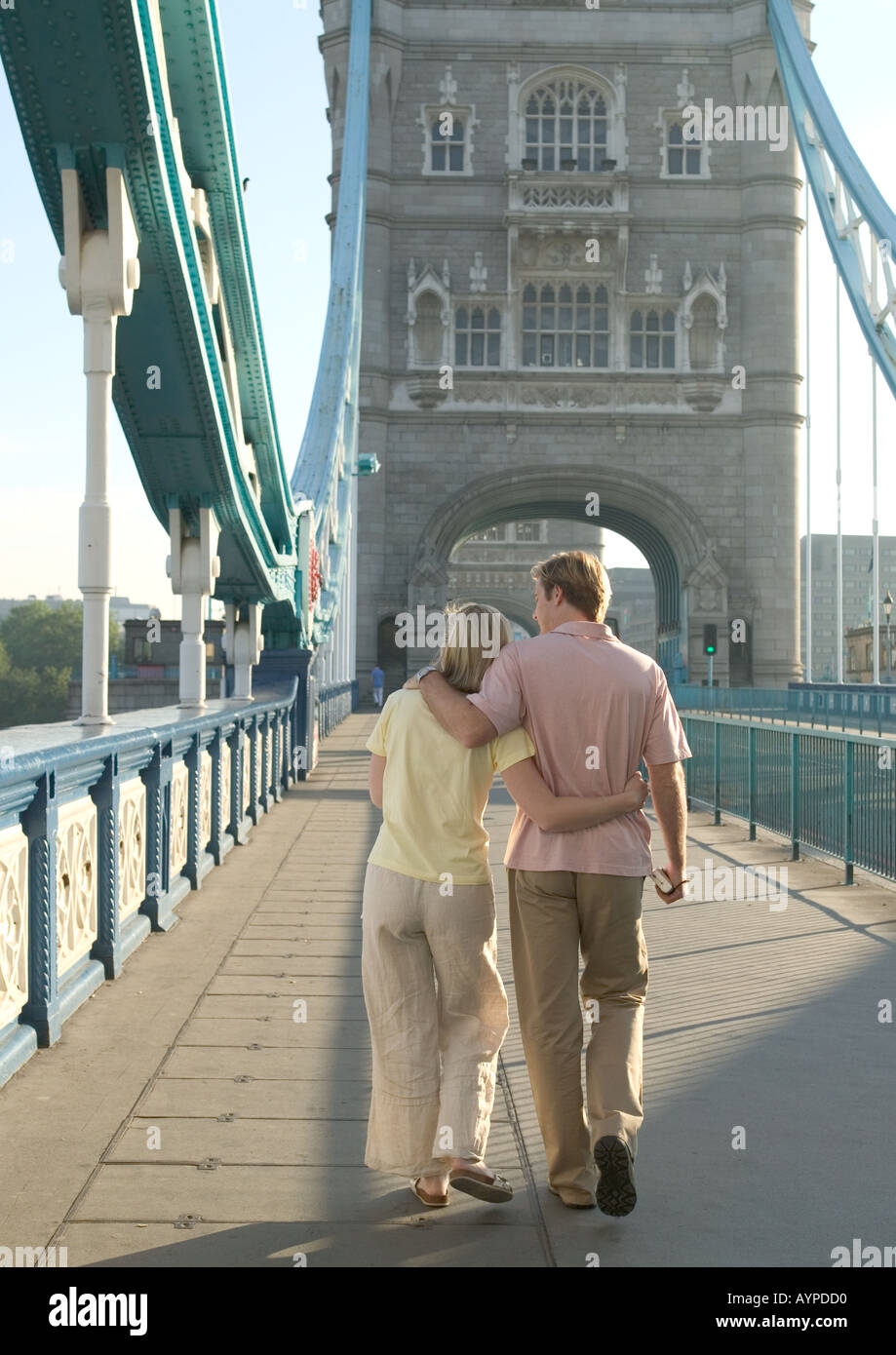 couple strolling over tower bridge arm in arm backs turned Stock Photo