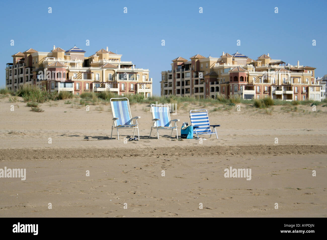 Holiday makers on the beach go for a swim leaving their empty chairs. Stock Photo