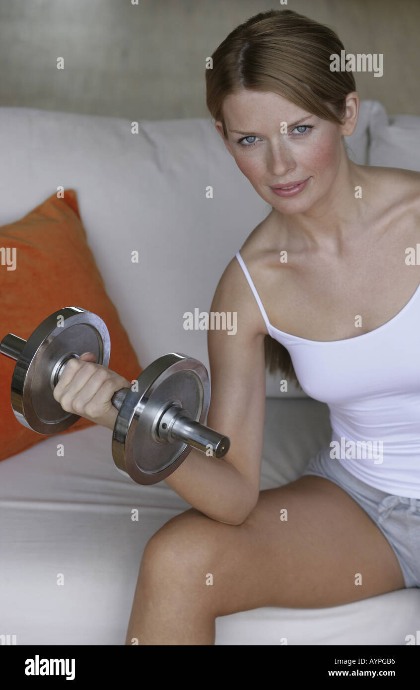 A blonde woman working out as she holds a dumbbell in her hand Stock Photo