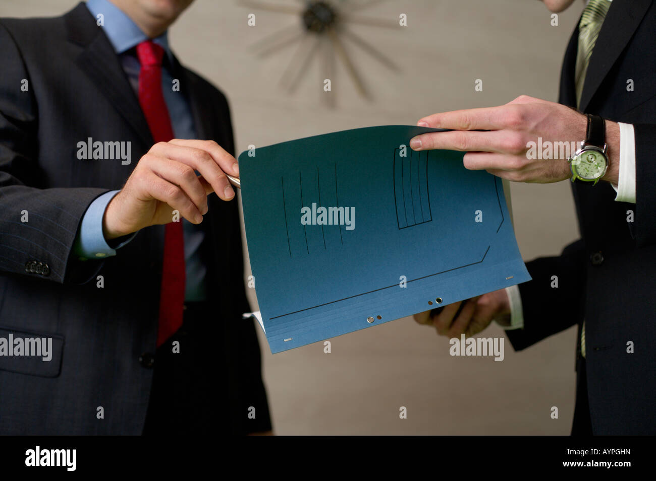 Two businessman standing in an office, handing over documents Stock Photo