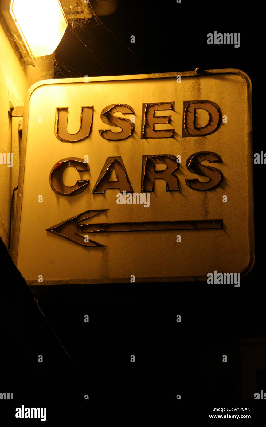 Used car sales sign showing serious signs of wear with arrow pointing