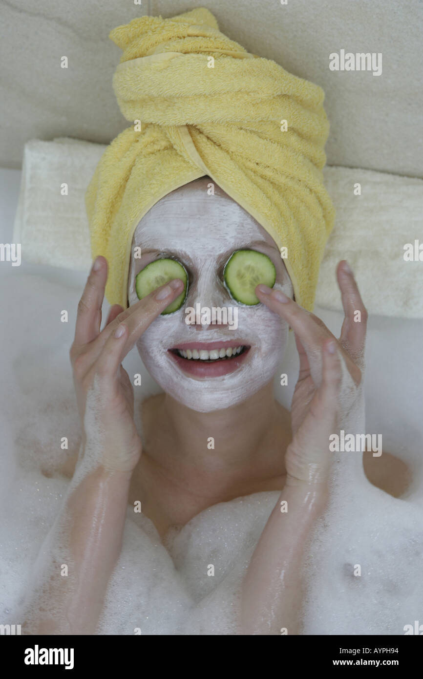 A woman relaxing in bathtub with cucumber slices on her eyes Stock Photo