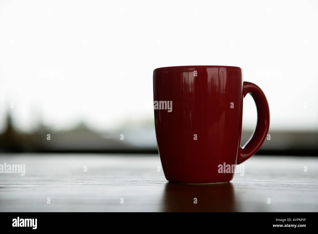 A red mug placed on a wooden table Stock Photo