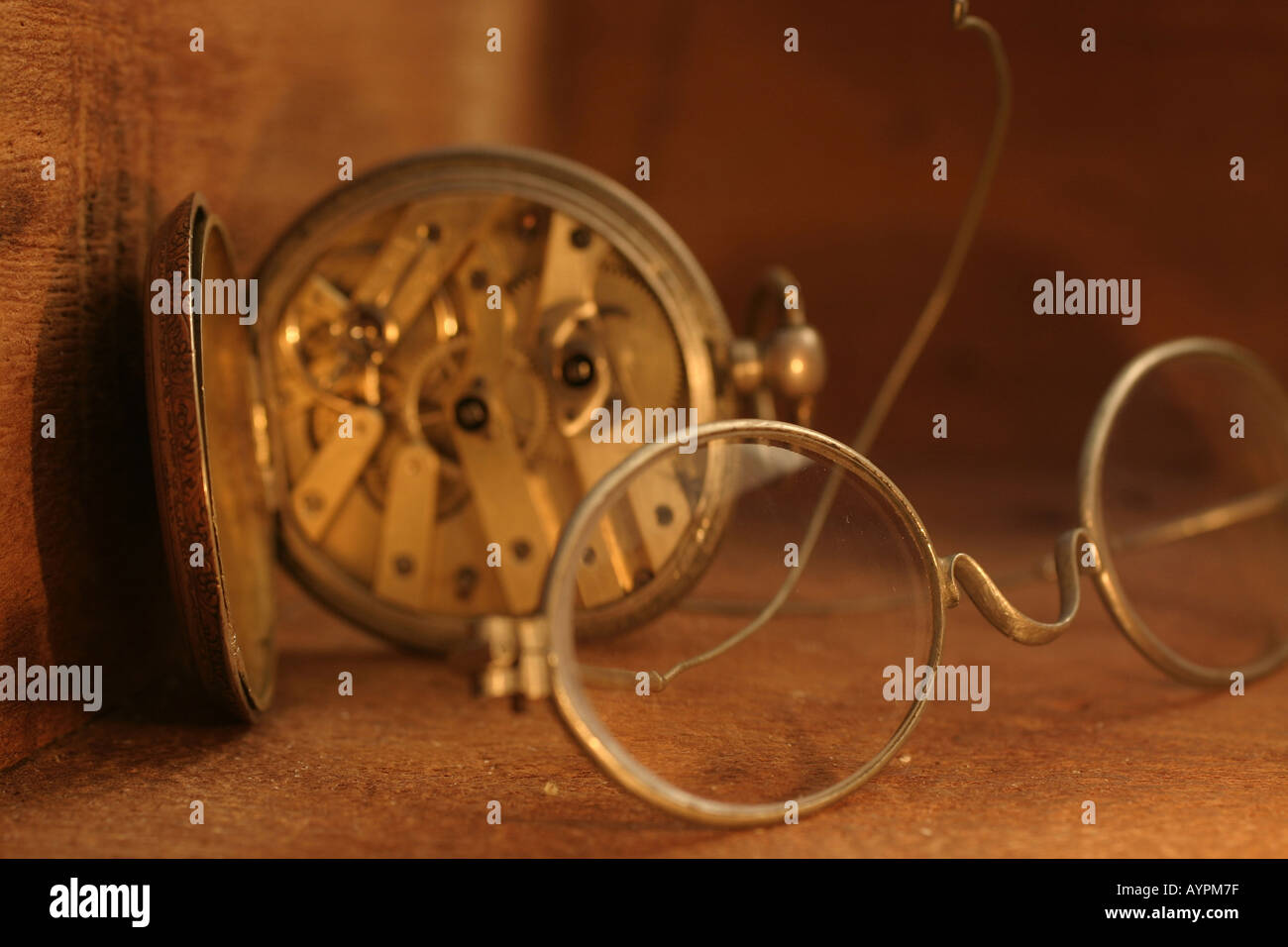 A pocket watch placed beside the glasses Stock Photo
