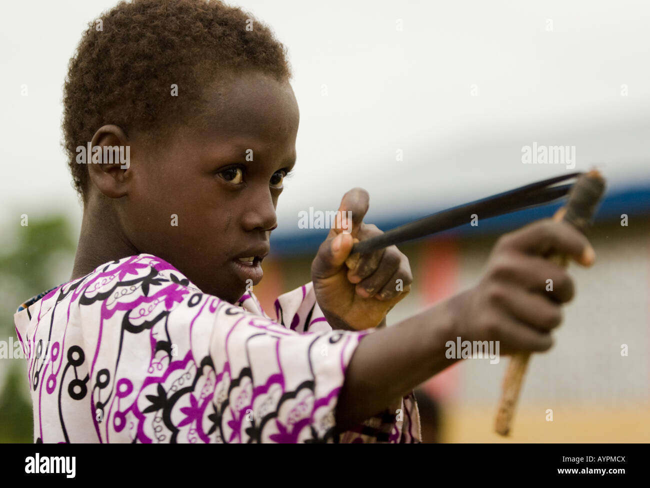 A boy plays with a sling shot, Ghana, Africa Stock Photo