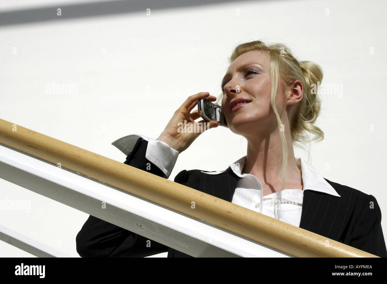 A professional woman converses over the mobile phone against the railing Stock Photo