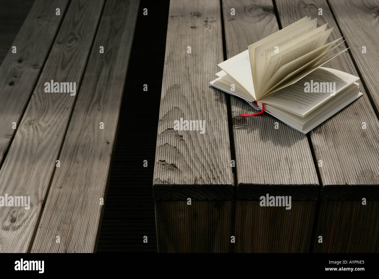 A novel placed on a wooden table with widespread pages Stock Photo