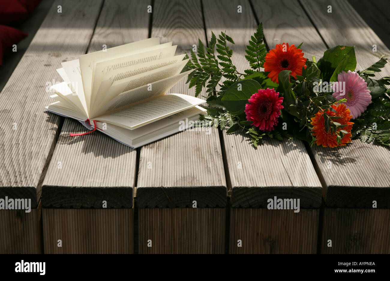 Bunch of flowers and a novel seen on a wooden table Stock Photo