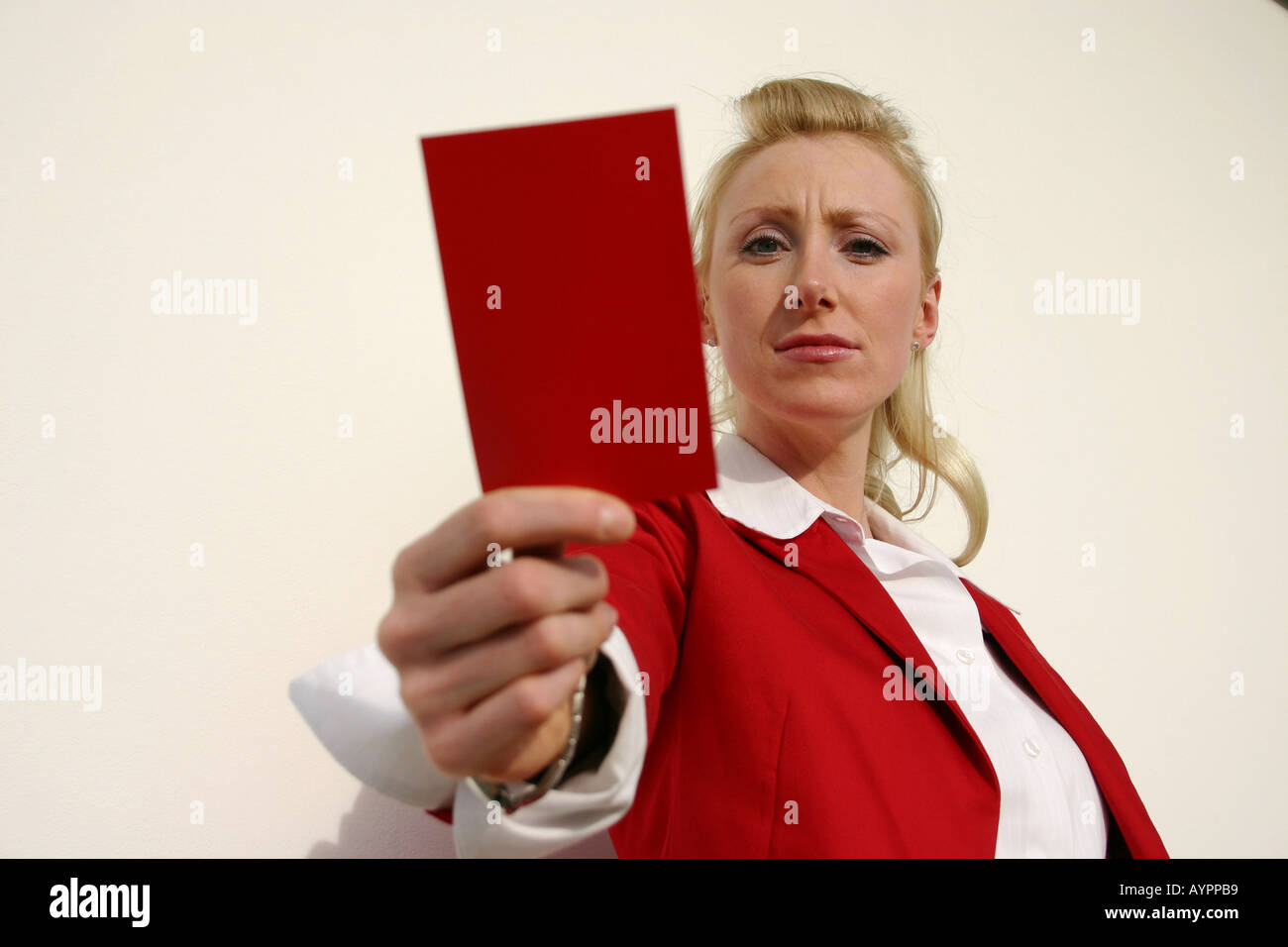 A woman wearing a red coat holds a red card in front of the camera Stock Photo