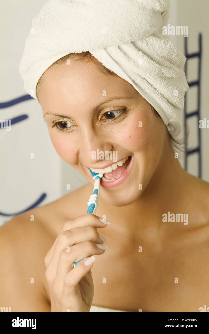 A young woman smiles while brushing her teeth Stock Photo