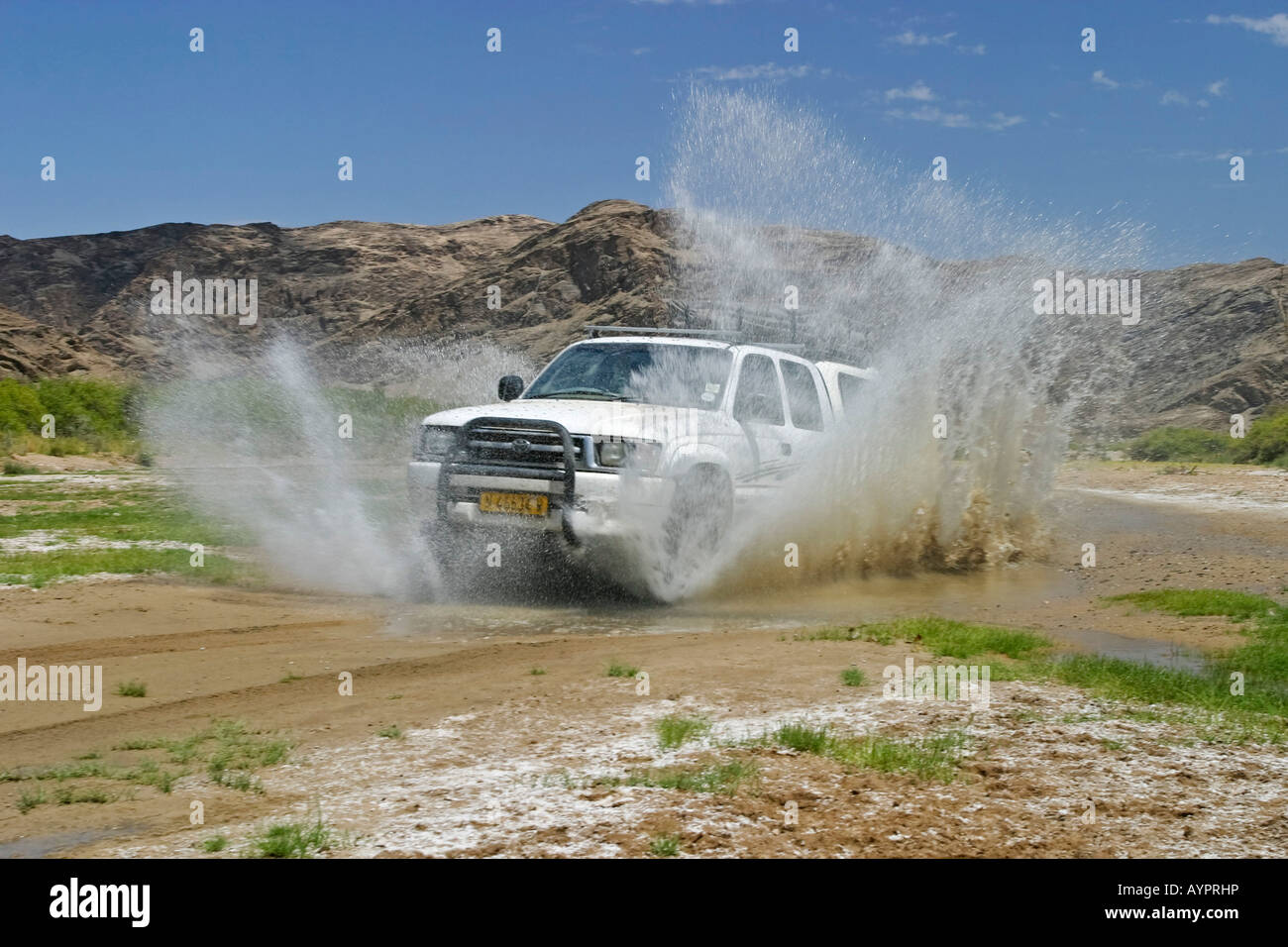 Off-road vehicle (4X4) driving through a large puddle in the otherwise dried-up Huanib River Valley, Kaokoveld, Namibia, Africa Stock Photo