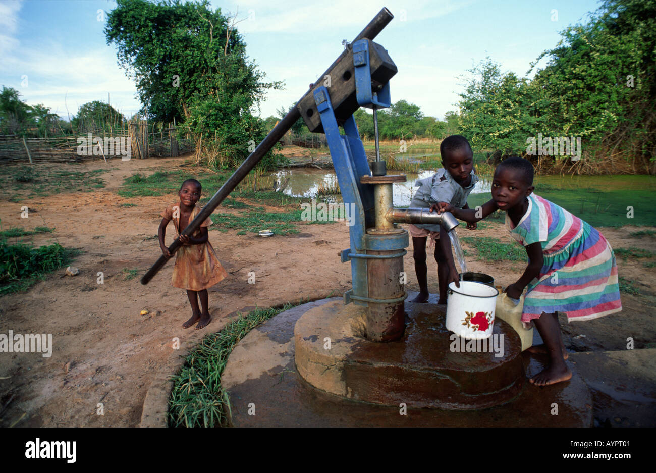 Young rural BaTonga girls pumping water from their village well, a job they do 4 times a day. Nr Binga, Zimbabwe Stock Photo