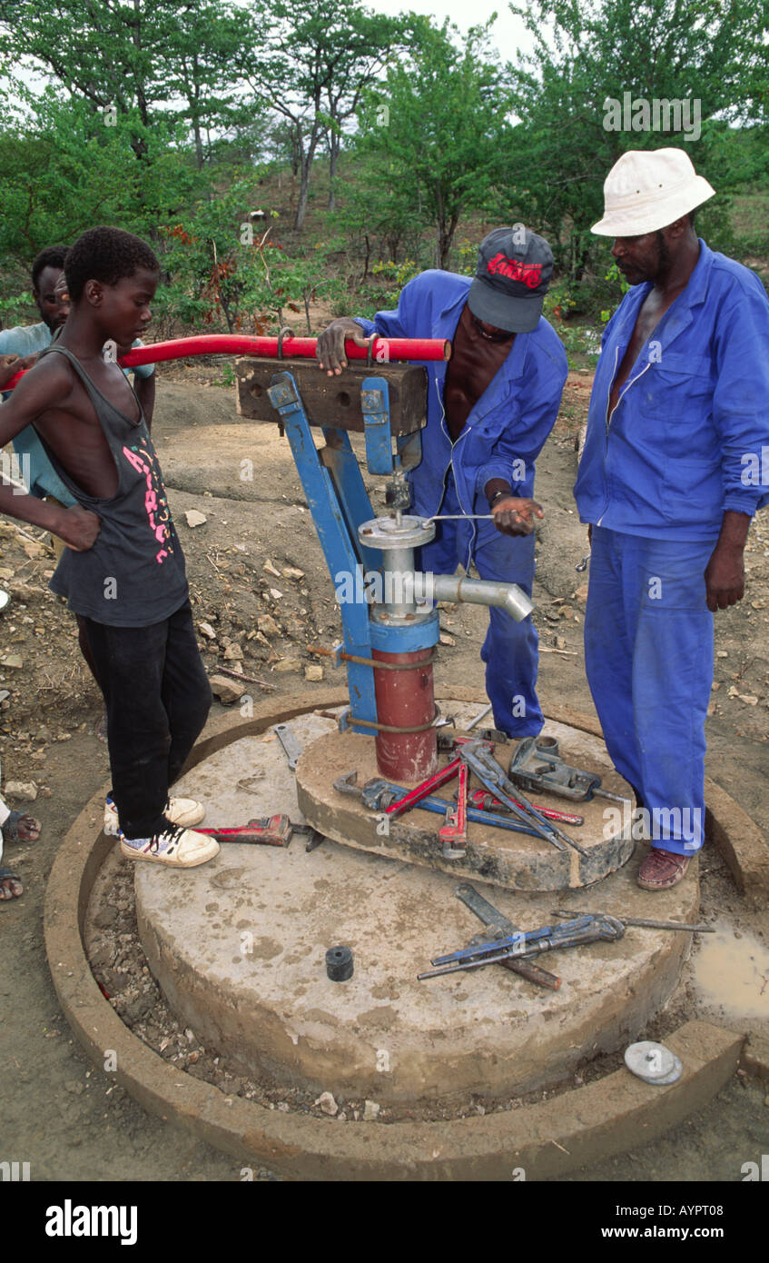 Water engineers fitting a pump head to new community water pump. Zimbabwe Stock Photo