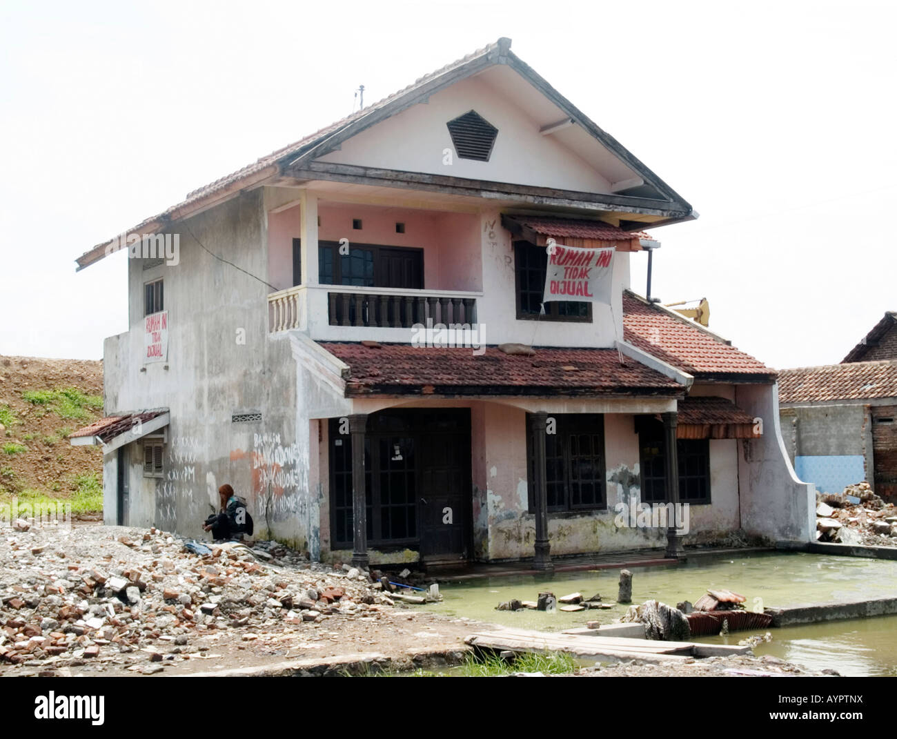 Woman house owner sitting in despair in the shadow of her now worthless house,Sidoarjo,East Java,Indonesia. Stock Photo