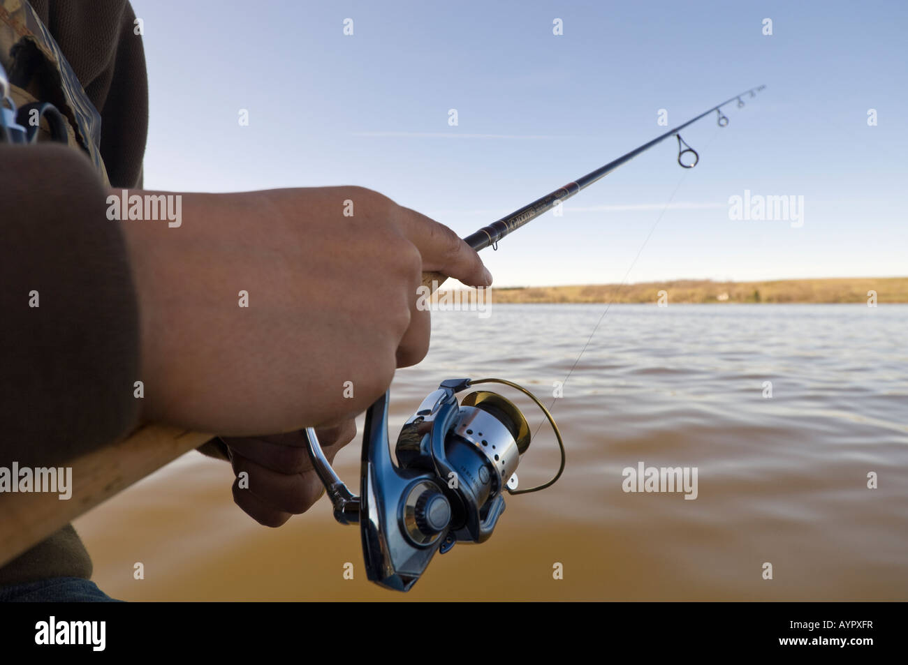 CLOSE UP OF HAND HOLDING FISHING POLE WITH SPINNING REEL Stock Photo