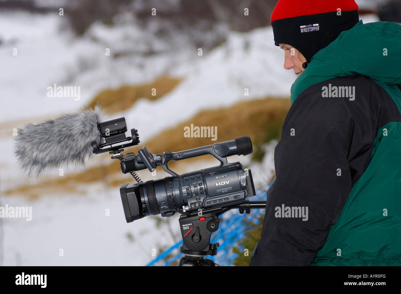 Camerawoman wearing down-filled jacket filming, wintertime, northern Norway, Scandinavia Stock Photo