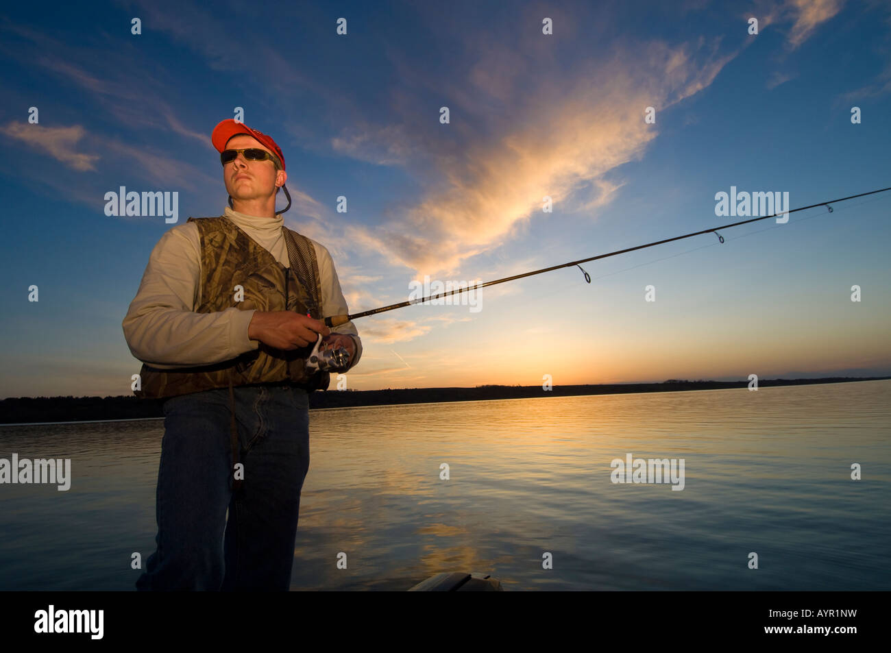 A FISHERMAN FISHES FROM A BOAT FOR WALLEYES AT DUSK ON BIG STONE LAKE