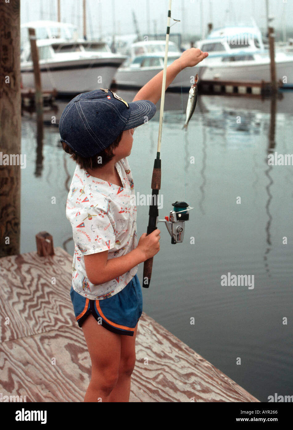 Six year old boy on dock holding tiny fish on the end of his fishing