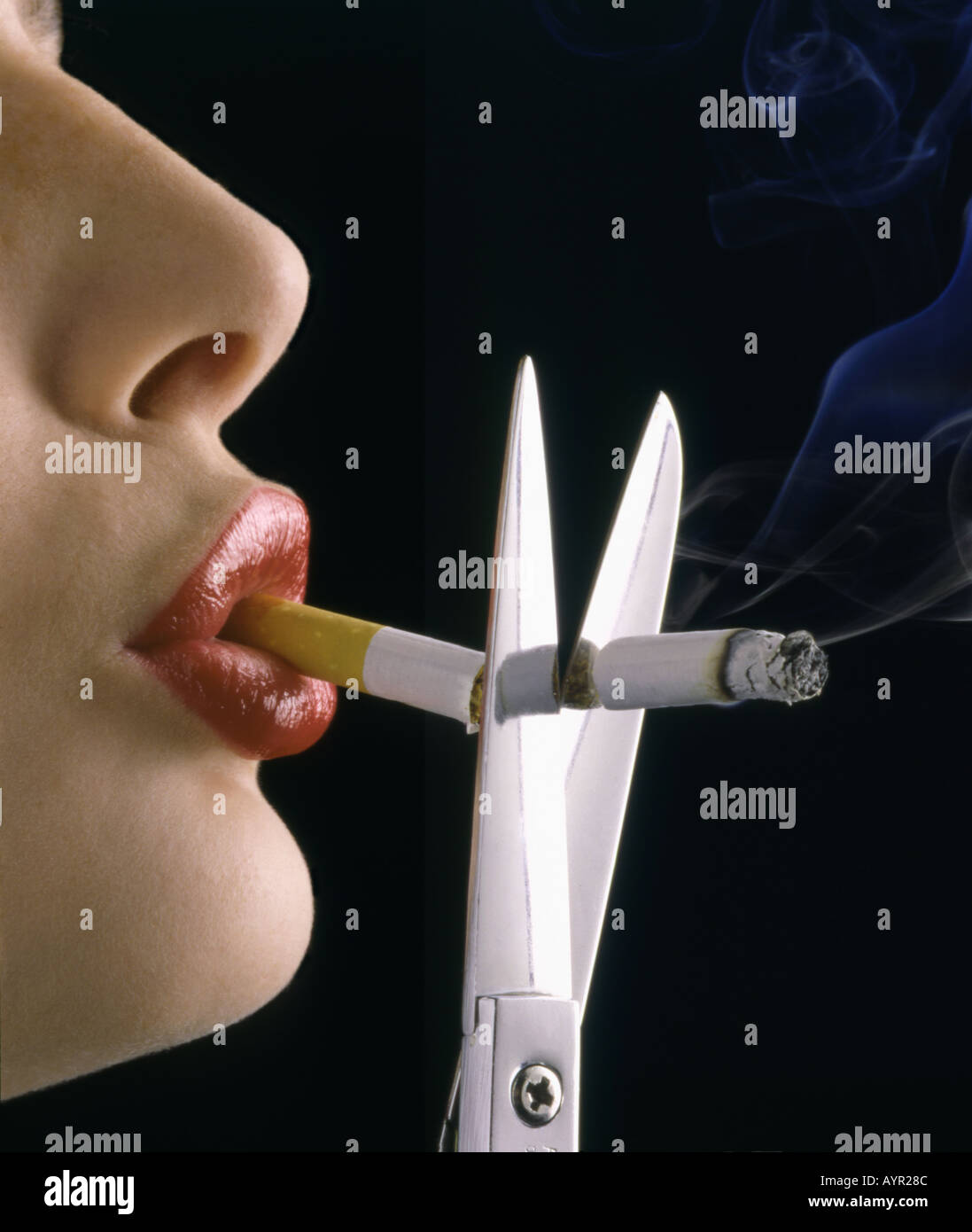 close up of woman with cigaretter in her mouth cutting it in half with scissors Stock Photo