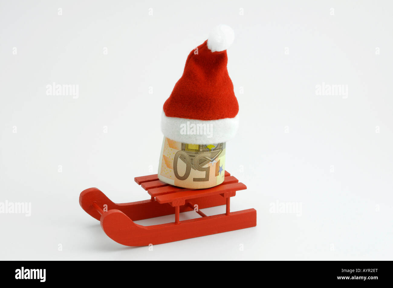 Rolled 50-Euro note wearing Santa hat riding a sleigh, symbol for Christmas bonus Stock Photo