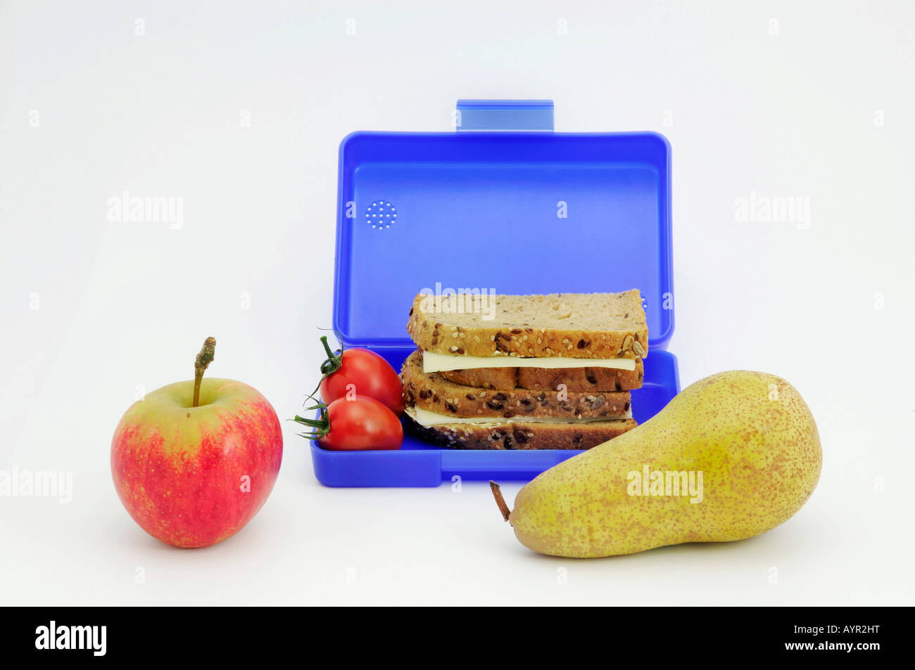 Blue breadbox filled with sandwiches and tomatoes, fruit in foreground Stock Photo