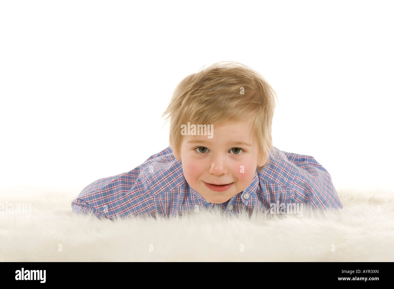 Two-year-old boy laying on fuzzy rug Stock Photo