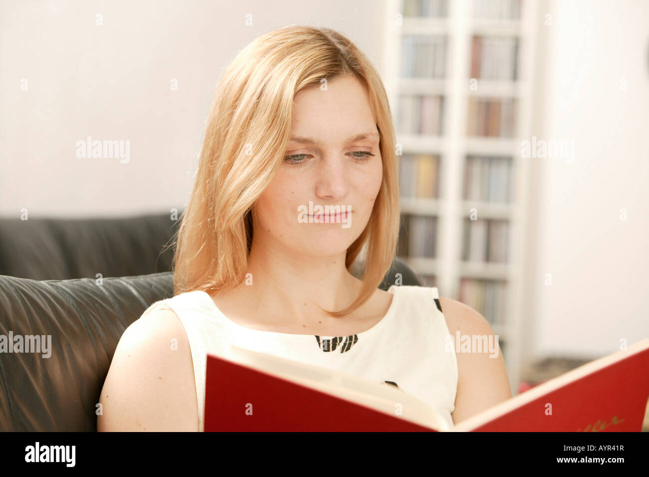 Young blonde woman reading red book Stock Photo
