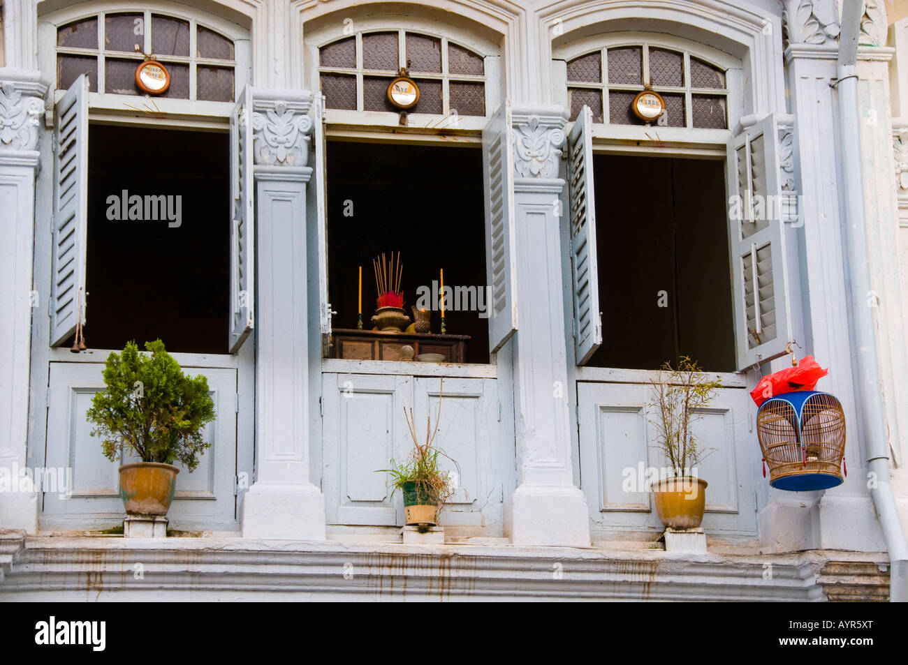 Three open windows with shutters on second story apartment in Singapore Stock Photo