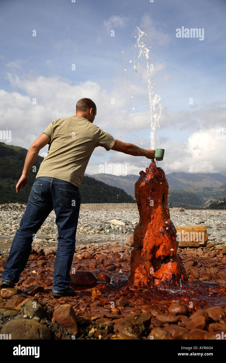 Man filling mug from natural spring. Jvari Pass, Georgian Military Highway, Georgia, Southwest Asia Stock Photo