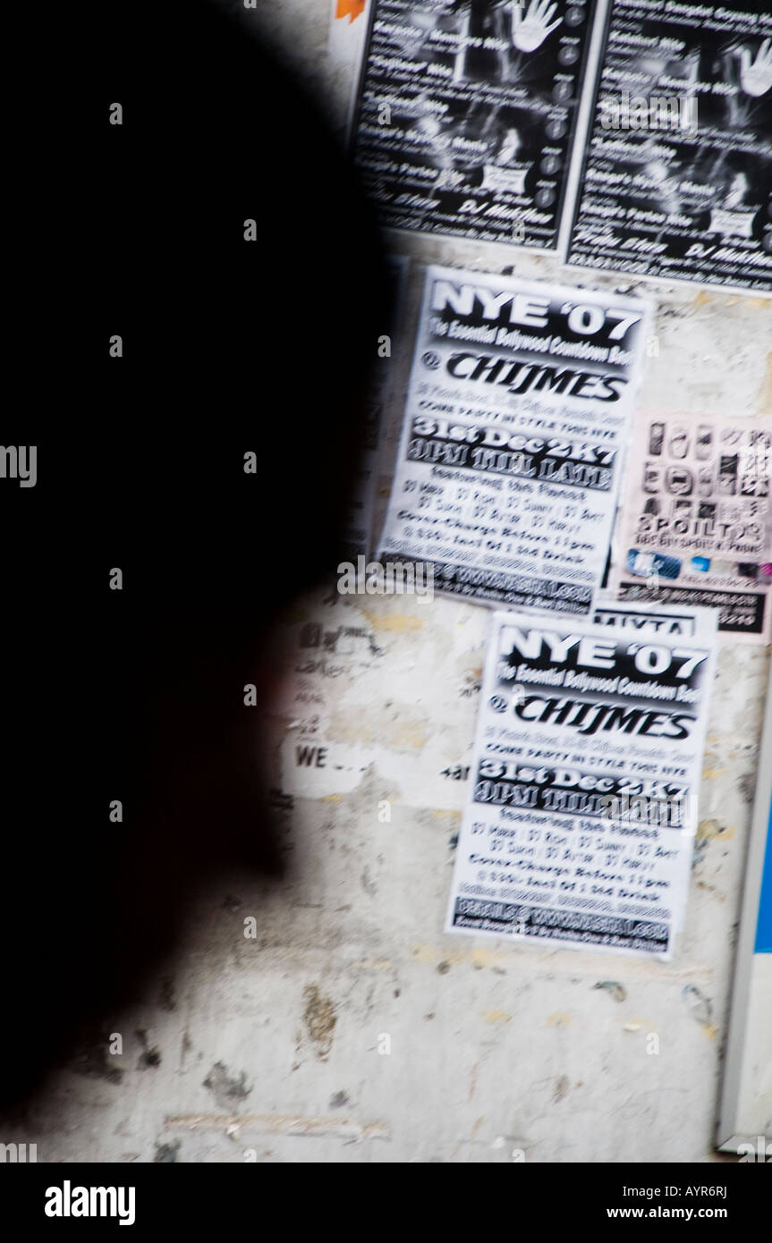 Sillhouette of blurred face against wall with advertisements Stock Photo
