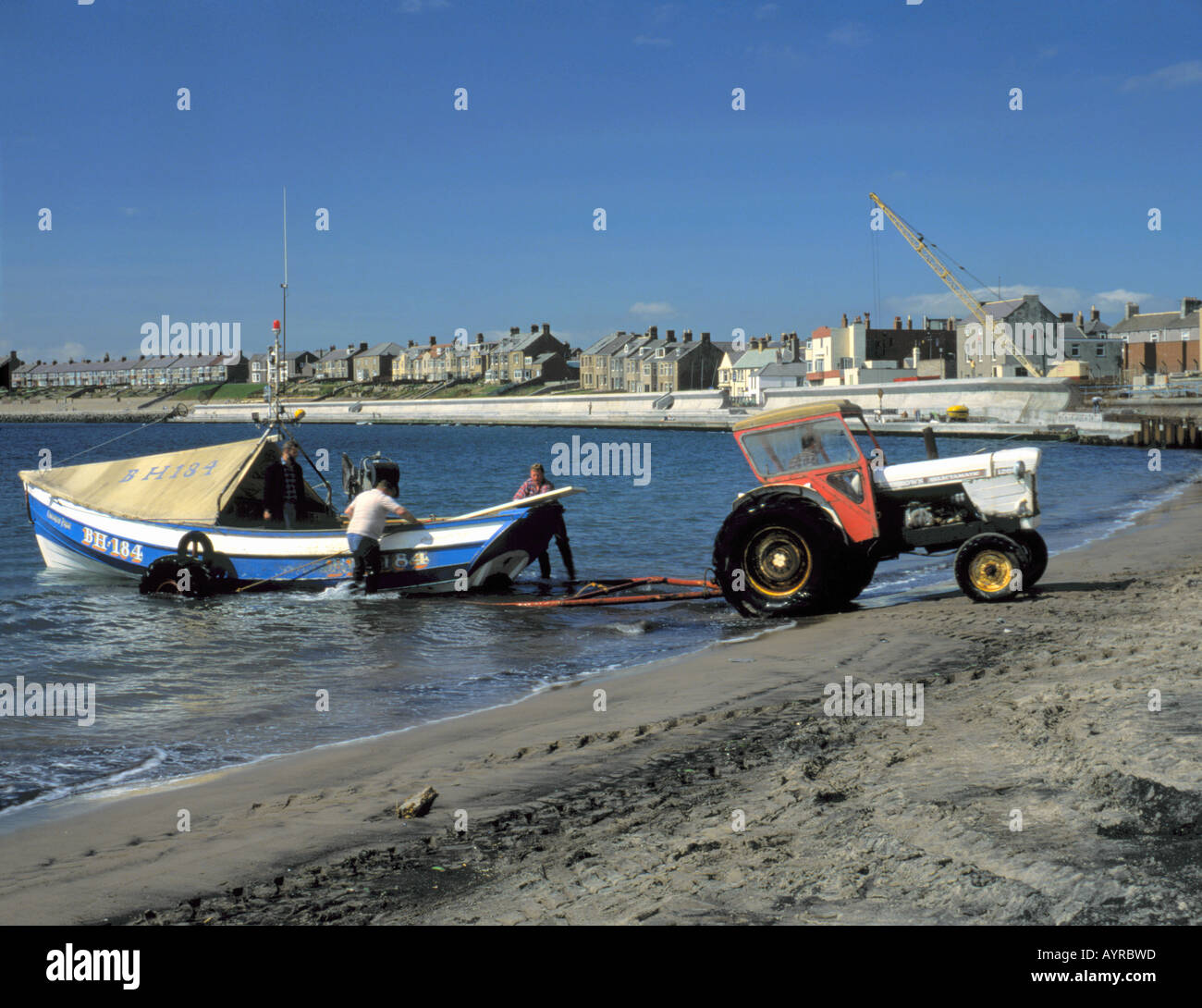Loading a traditional wooden coble fishing boat on to a trailer, Newbiggin-by-the-Sea, Northumberland, England, UK. Stock Photo