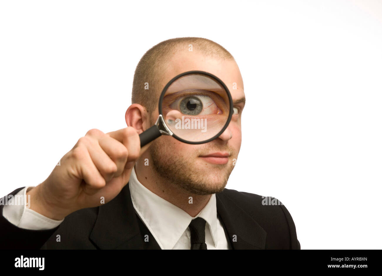 Young man holding magnifying glass in front of his face Stock Photo