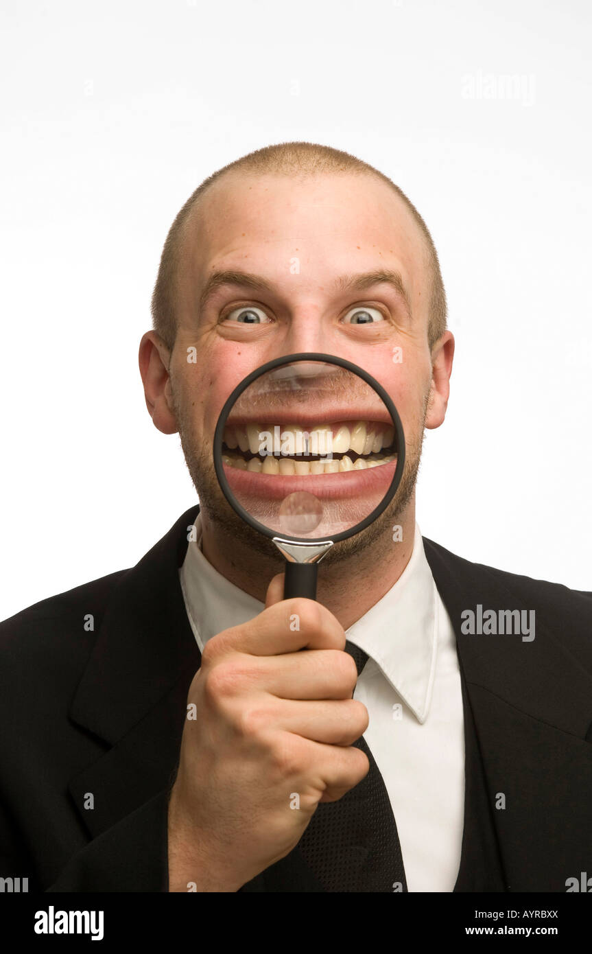 Young man holding magnifying glass in front of his mouth Stock Photo